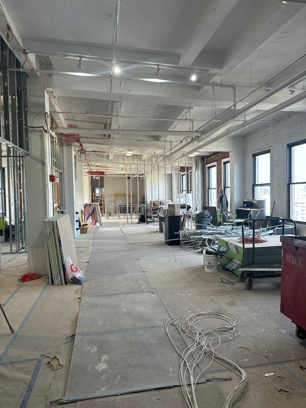 In-progress commercial installation showing a modern open-plan space in rough-in stage with exposed concrete